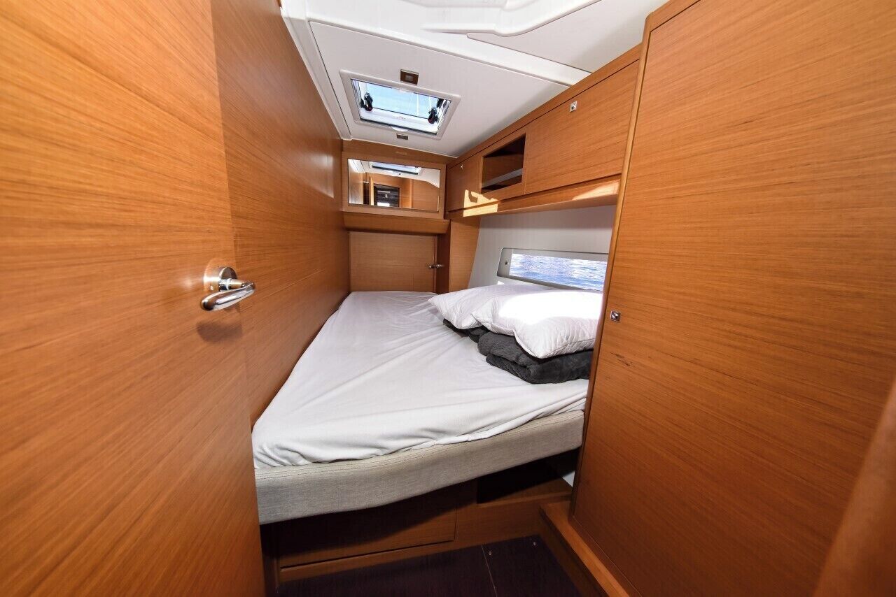 A compact, well-lit interior with a bed, a small window, and a ceiling-mounted light fixture.