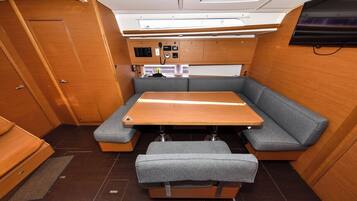 A compact RV interior with a wooden table, grey cushioned seating, and a control panel.