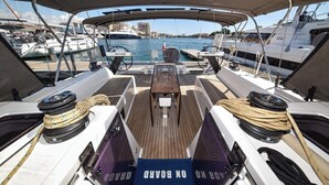 Ein Bootsdeck mit Tisch, Seilen und Blick auf den Yachthafen.