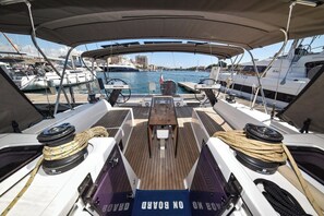 Ein Bootsdeck mit Tisch, Seilen und Blick auf den Yachthafen.