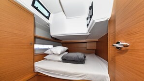 Une cabine compacte et bien éclairée, équipée d’un lit, d’oreillers et d’une petite table.
