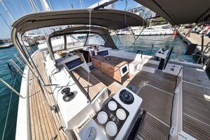 A boat deck with a wooden floor, a seating area, and a small table with a screen.
