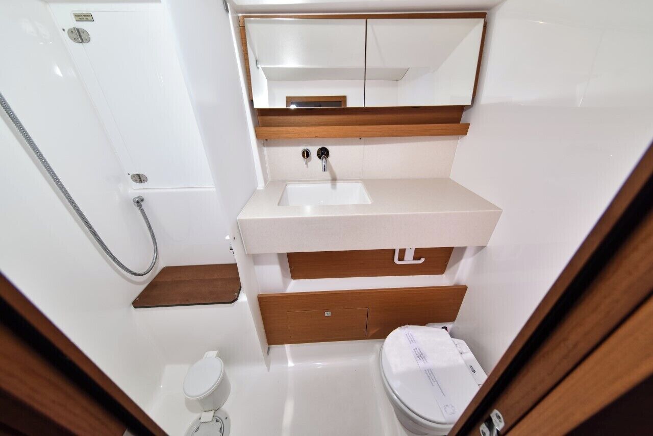 A compact bathroom with a shower, a sink, a toilet, and a mirror above the sink.