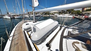 Un port de plaisance où sont amarrés plusieurs voiliers, avec une terrasse en bois et un auvent blanc.