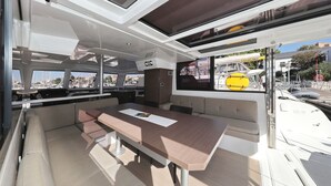 Et moderne interiør med et stort bord, siddepladser og udsigt til lystbådehavnen.