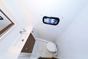 Et lille badeværelse med toilet, håndvask og et vindue.