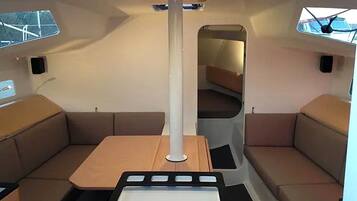A compact interior with a central table, cushioned seating, and a large mirror.