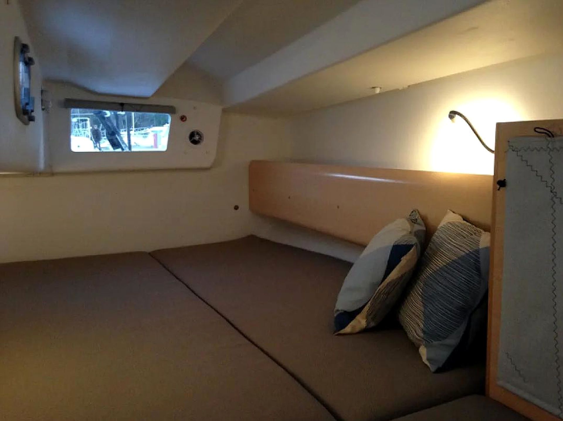 A small, compact room with a bunk bed, a window with a view, and a wall-mounted heater.