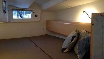 A small, compact room with a bunk bed, a window with a view, and a wall-mounted heater.
