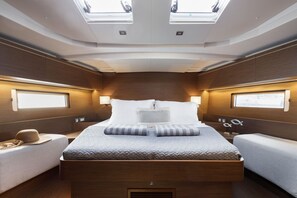 Un intérieur moderne avec un lit central, deux tables de chevet et une lucarne.