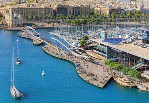 A marina with boats, a pedestrian bridge, and a building with a sloped roof.