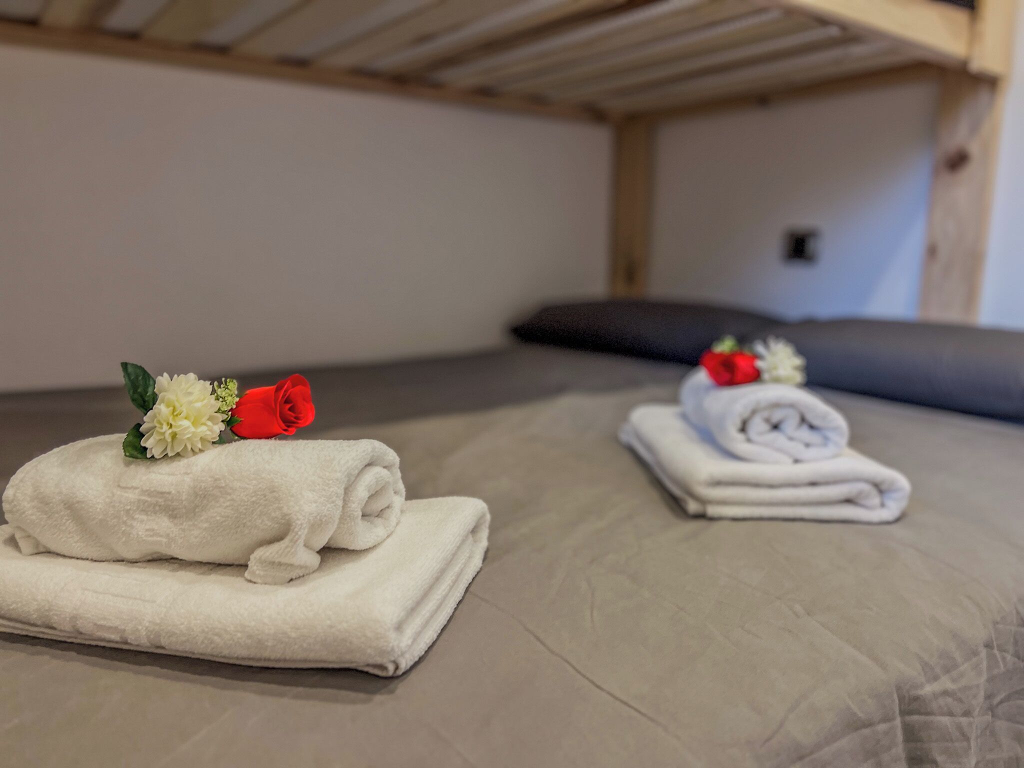 A neatly made bed with two towels, each adorned with a flower and a fruit.
