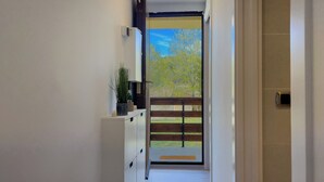 A hallway leading to a sliding glass door with a view of a wooden deck and trees.