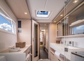 A modern bathroom with a skylight, a walk-in shower, and a vanity with a mirror.