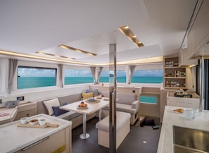 A modern interior with a dining area, kitchen, and large windows overlooking the sea.