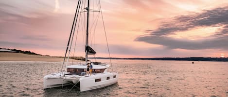 Un velero blanco sobre aguas tranquilas con un atardecer de fondo.