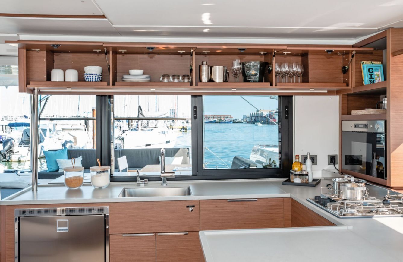 A modern kitchen with a view of the marina, built-in shelves, and a stainless steel refrigerator.