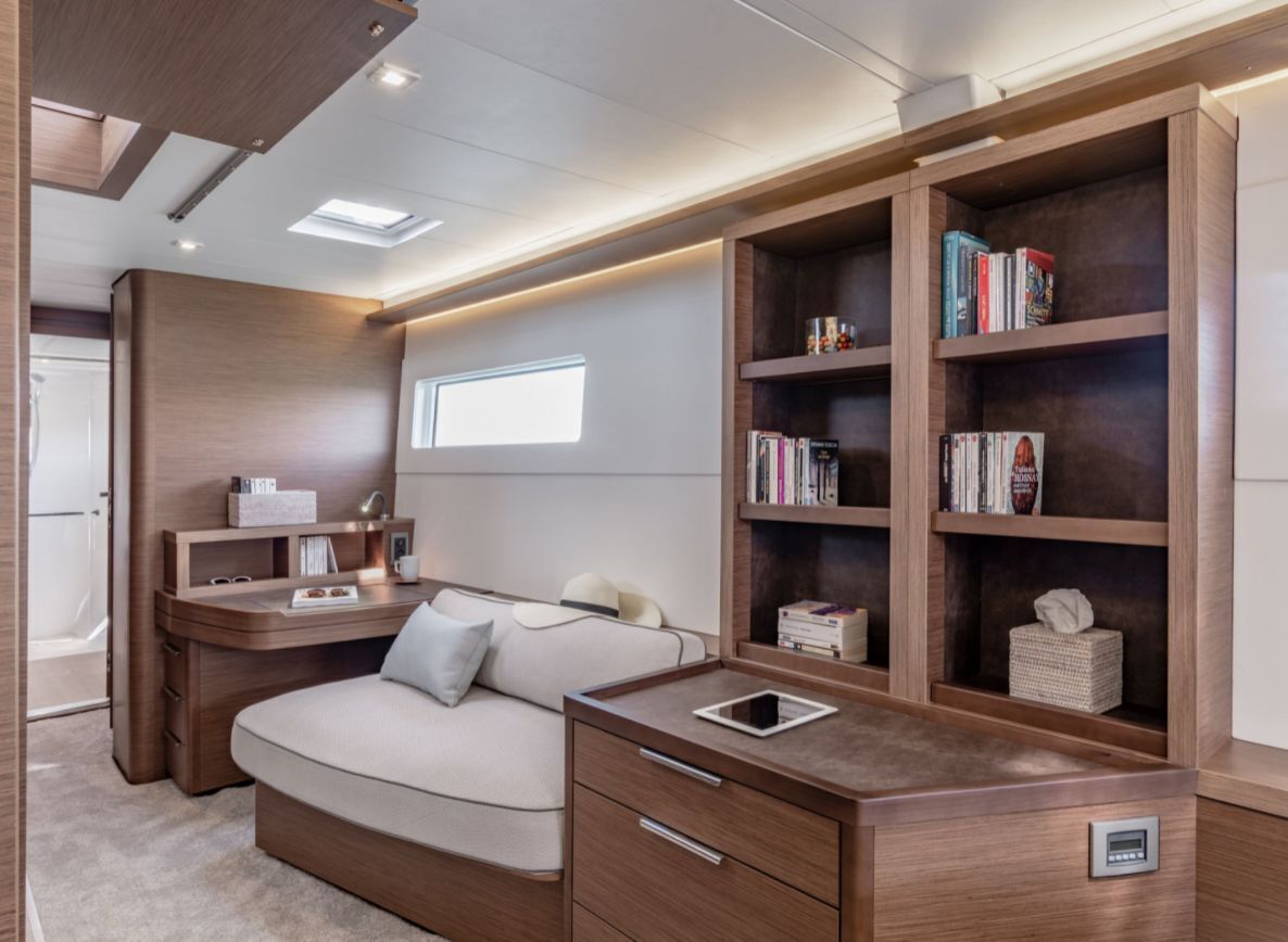 A modern bedroom with a built-in desk, bookshelves, a sofa, and a bedside table.