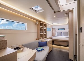A compact, well-lit interior with a bed, bedside tables, a sofa, and a bookshelf.