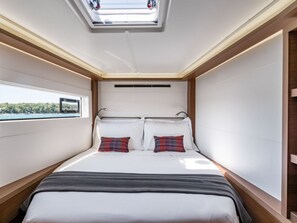 A compact bedroom with a skylight, a bed with white linens, two pillows, and a view of the outdoors. - Sun-Kissed Sailing Adventure in the Cyclades Islands (Thira)