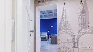 Un pasillo con una puerta que da a una habitación con pared azul y un dibujo de un edificio en la pared.