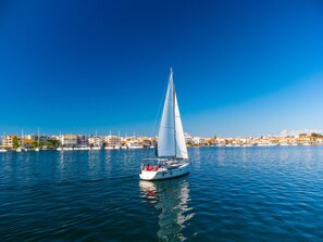 A sailboat on calm water with a cityscape in the background. - Sun-kissed Sailing Adventure in the Ionian Islands (Preveza)
