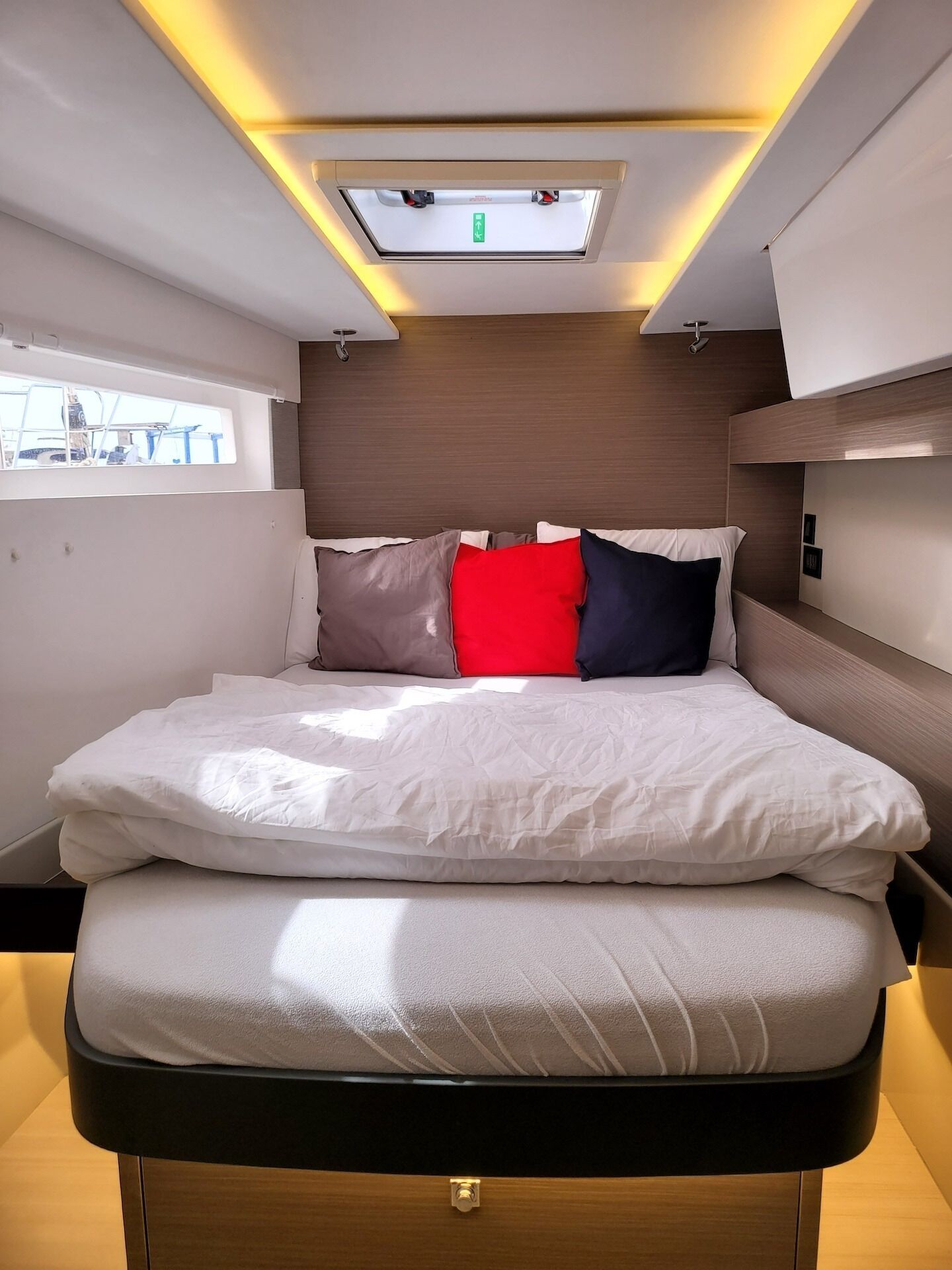A compact, well-lit room with a bed, a window, and a skylight.