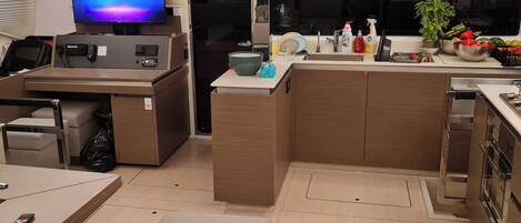 Une cuisine moderne dotée d’un téléviseur encastré, d’un petit coin repas et d’un coin cuisine.
