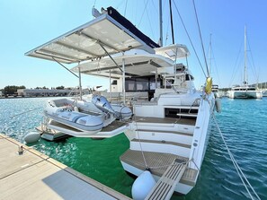A yacht docked at a marina with a covered deck area, a small inflatable boat, and a wakeboard. - Sun-Kissed Sailing Adventure in Zadar, Croatia (Bibinje)