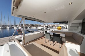 A yacht deck with a seating area, a table, and a view of the marina. - Sun-kissed Sailing Adventure in Split-Dalmatia, Croatia (Trogir)