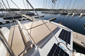 Ein Yachthafen mit mehreren angedockten Booten, wolkenlosem Himmel und ruhiger Wasserfläche.