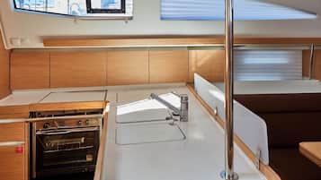 Een kleine keuken met een ingebouwde oven, een spoelbak en een raam boven de aanrecht.