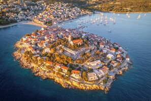 An aerial view of a coastal town with a central island featuring a mix of residential and commercial buildings, surrounded by a marina with boats. - Sun-Kissed Sailing Adventure in Sibenik, Croatia (Primošten)