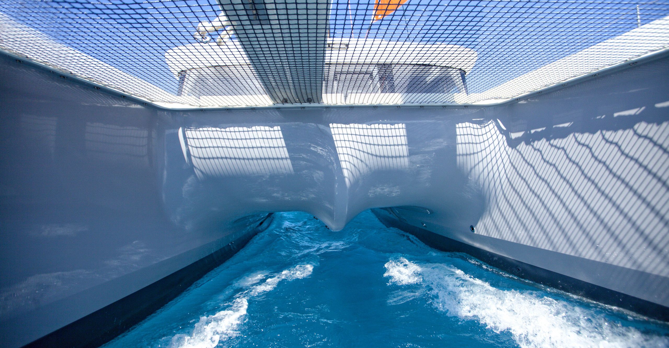 An indoor swimming pool with clear water, surrounded by walls with a mesh pattern.