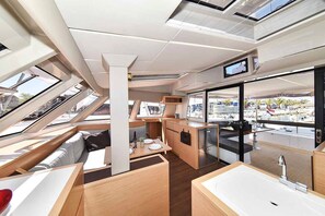 A modern interior with a kitchen area, dining space, and a large window offering a view of the marina.