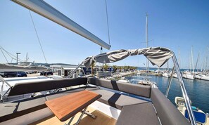 Un port de plaisance avec des bateaux amarrés, un espace de repos couvert avec une table, et un ciel dégagé.