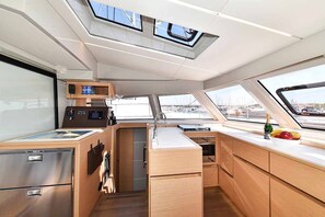 A compact galley with a central sink, wooden cabinetry, and a small refrigerator.