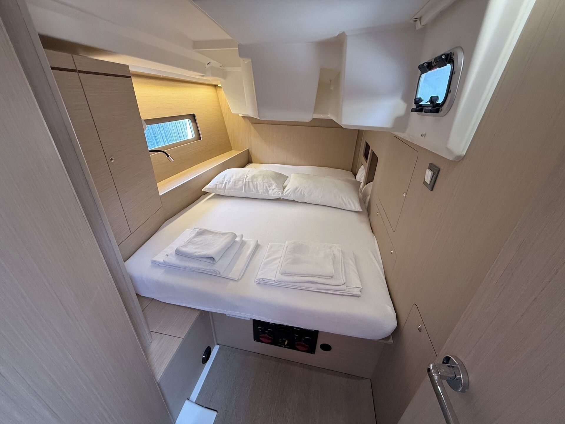 A compact, well-lit cabin with a single bed, a small window, and a control panel.