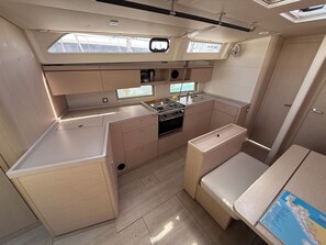 A compact galley with a stove, sink, and storage cabinets. - Sun-Kissed Sailing Adventure in Zadar, Croatia (Bibinje)