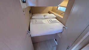 A compact room with a bed, pillows, and a small window. - Sun-Kissed Sailing Adventure in Zadar, Croatia (Bibinje)