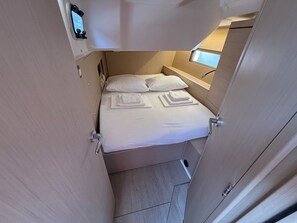 A compact room with a bed, pillows, and a small window. - Sun-Kissed Sailing Adventure in Zadar, Croatia (Bibinje)