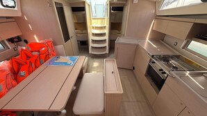A compact kitchen with a stove, a dining table, and storage cabinets. - Sun-Kissed Sailing Adventure in Zadar, Croatia (Bibinje)