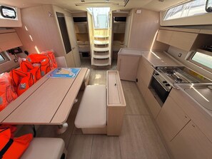 A compact kitchen with a stove, a dining table, and storage cabinets. - Sun-Kissed Sailing Adventure in Zadar, Croatia (Bibinje)