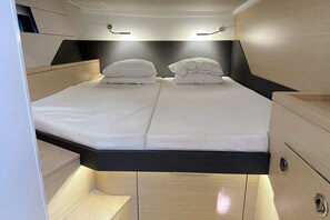 A compact, modern bed with two pillows, built-in lighting, and a wooden finish. - Sun-Kissed Sailing Adventure in Istria, Croatia (Pula)