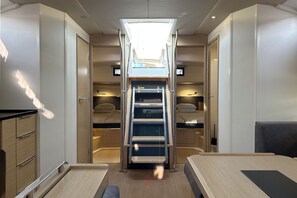 A compact interior with a central aisle leading to a bunk bed area, a small table, and a bench. - Sun-Kissed Sailing Adventure in Istria, Croatia (Pula)