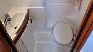 Casa de banho compacta com sanita, lavatório e zona de duche.