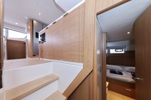 Ein kompakter, moderner Innenraum mit einer Küchenzeile, einem Bett und einem kleinen Fenster.