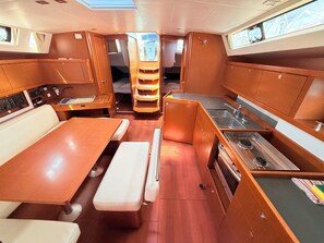 A compact galley with a dining table, bench seating, a small kitchenette, and a galley sink. - Sun-Kissed Sailing Adventure in Zadar, Croatia (Bibinje)