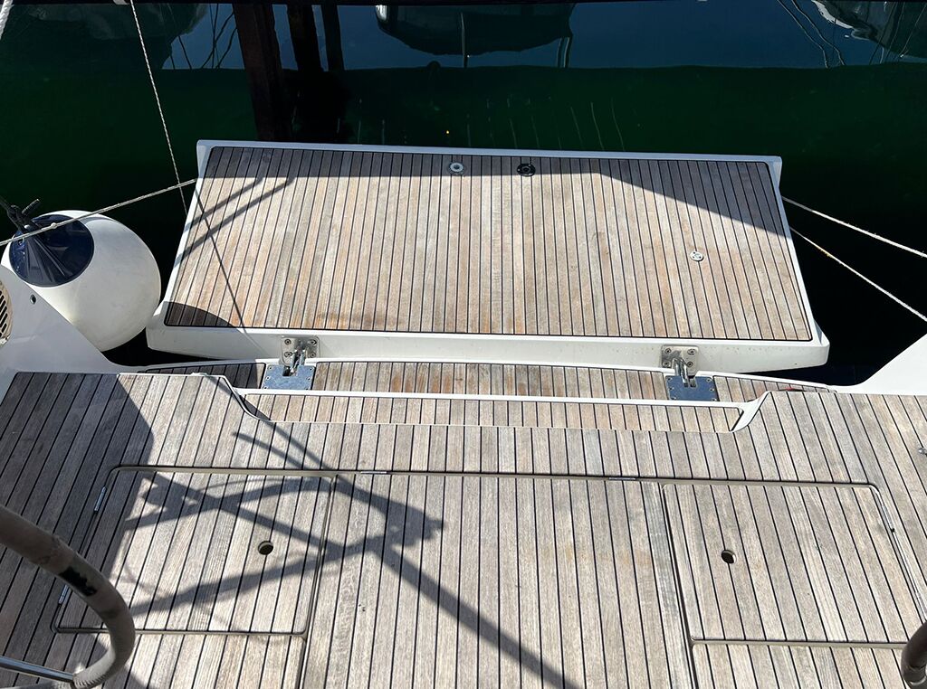A wooden deck with a metal railing and a white object on the left.