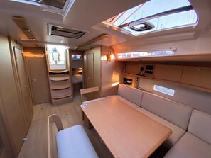 A compact interior with a dining area, a kitchenette, and a small seating space. - Sun-Kissed Sailing Adventure in the Saronic Islands (Lavrio)